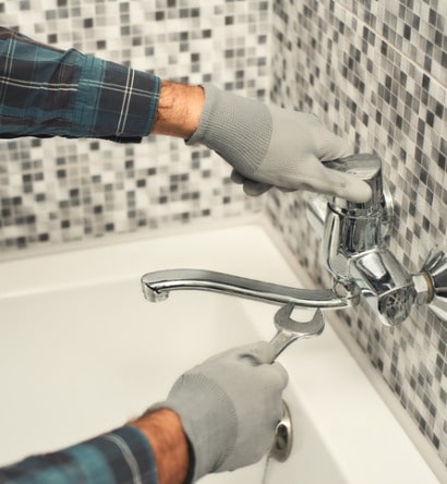 plumber-repairing-a-tap-in-the-bathroom-picture-id1170038016-min